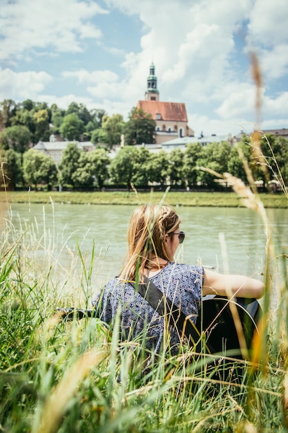 Im Freien Musik machen Junges Mädchen spielt Gitarre an einem Fluss im Sommer