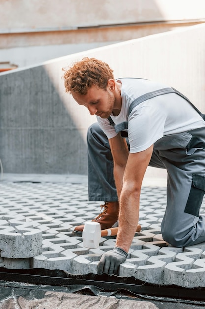 Im Freien sitzen Junger Mann, der tagsüber in Uniform auf dem Bau arbeitet