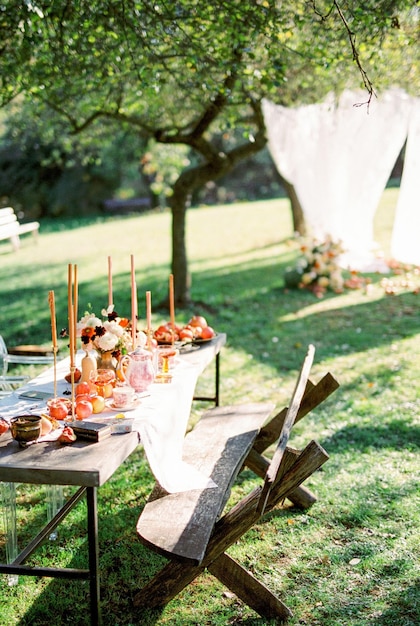 Im Garten steht ein mit Geschirr und Kerzen beladener Tisch