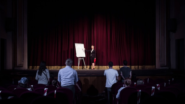 Im Gespräch mit Schülern. Sprecherin, die Präsentation in der Halle beim Workshop hält. Geschäftszentrum. Rückansicht der Teilnehmer im Publikum. Konferenzveranstaltung, Schulung. Bildung, Treffen, Geschäftskonzept.