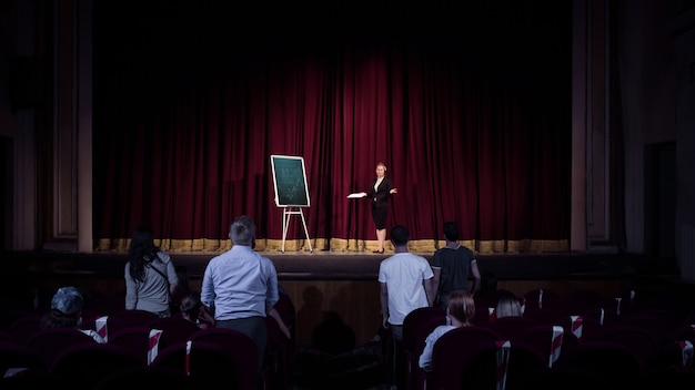 Im Gespräch mit Schülern. Sprecherin, die Präsentation in der Halle beim Workshop hält. Geschäftszentrum. Rückansicht der Teilnehmer im Publikum. Konferenzveranstaltung, Schulung. Bildung, Treffen, Geschäftskonzept.