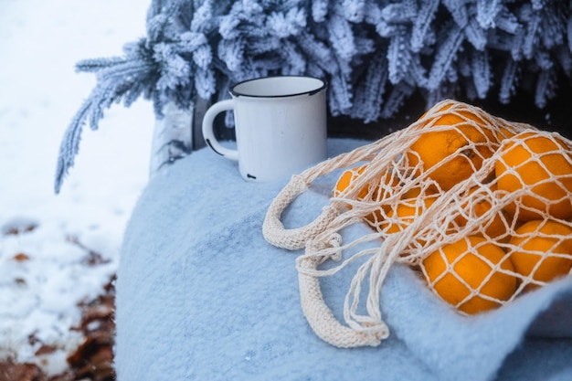 Im Kofferraum des Autos gibt es schneebedeckten Weihnachtsbaum und Mandarinen auf einer blauen Decke