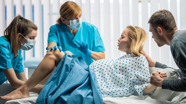 Im Krankenhaus drängt Frau in Wehen zur Geburt Geburtshelfer Helfender Ehepartner hält ihre Hand