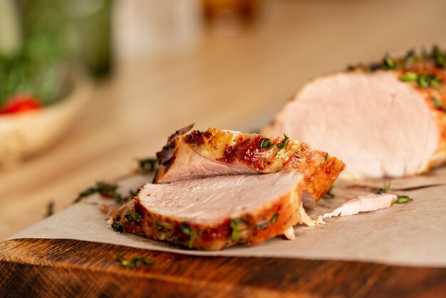 Im Ofen gebacken mit aromatischen Kräutern saftiges Schweinefilet in dünne Scheiben geschnitten auf Holzbrett in der Küche zu Hause