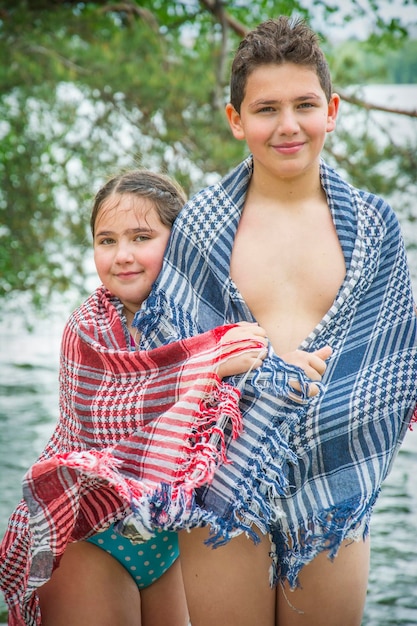 Im Sommer werden Bruder und Schwester nach dem Schwimmen im Fluss in ein Handtuch gewickelt