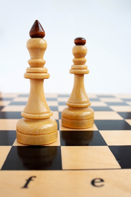 Im Vordergrund auf dem Schachbrett steht der weiße König hinter der Dame.
