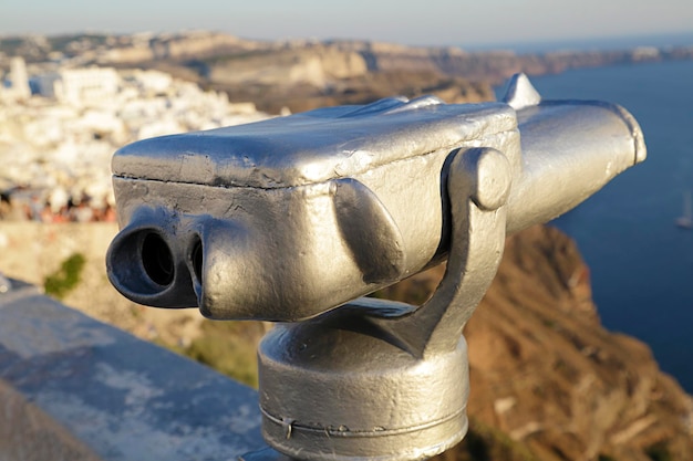 Im Vordergrund ein münzbetriebenes Teleskop im Hintergrund ein Blick auf die Stadt Fira Insel Santorini Griechenland