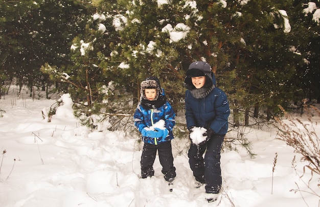 Im Winter spielen zwei Jungen im Park mit Schnee. Brüder auf einem Spaziergang