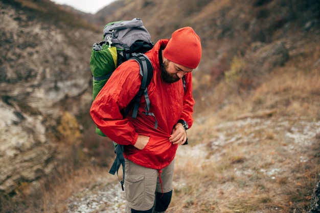 Imagem ao ar livre do homem alpinista extremo caminhando nas montanhas com mochila de viagem Viajante barbudo se preparando para o montanhismo Pessoas de viagem e conceito de estilo de vida saudável