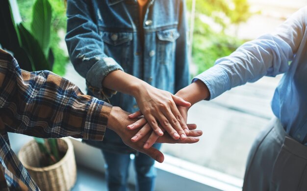 Imagem aproximada da equipe de negócios em pé e juntando as mãos no escritório