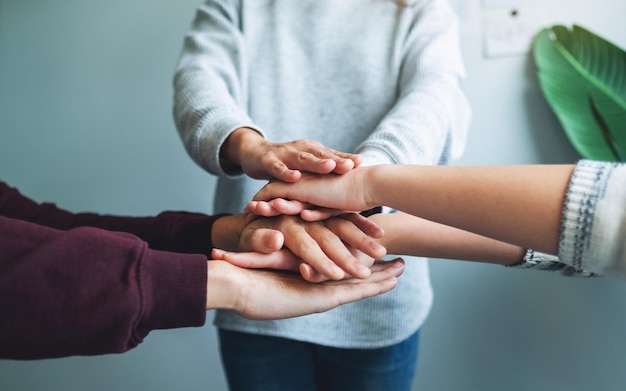 Imagem aproximada da equipe de negócios em pé e juntando as mãos no escritório