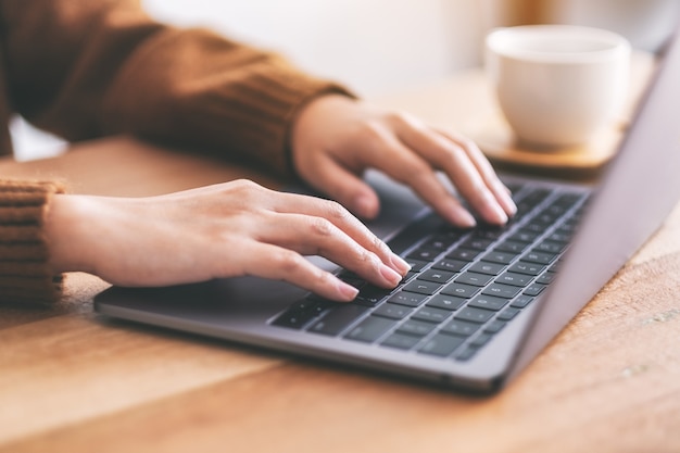 Imagem aproximada das mãos de uma mulher usando e digitando no teclado do laptop