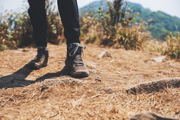 Imagem aproximada das pernas de uma mulher com botas de trekking no topo de uma montanha