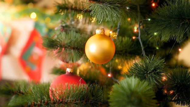 Imagem aproximada de bugiganga dourada de Natal pendurada em um pinheiro na sala de estar da casa contra a lareira