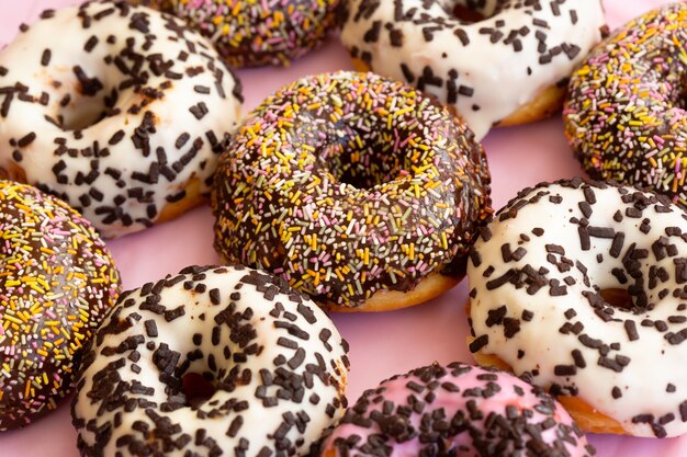 Imagem aproximada de deliciosos donuts coloridos com granulado e flocos de chocolate