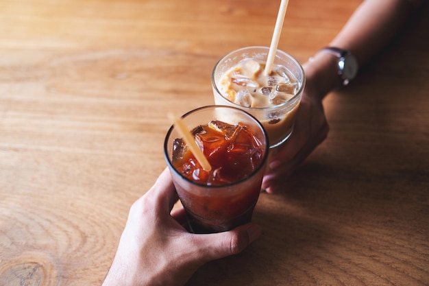 Imagem aproximada de duas pessoas tilintando copos de café no café