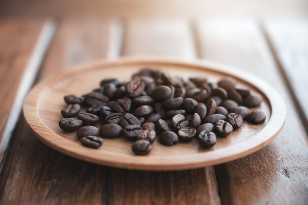 Imagem aproximada de grãos de café em um pires de madeira em cima da mesa