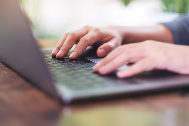 Imagem aproximada de mãos usando e digitando no teclado do laptop na mesa