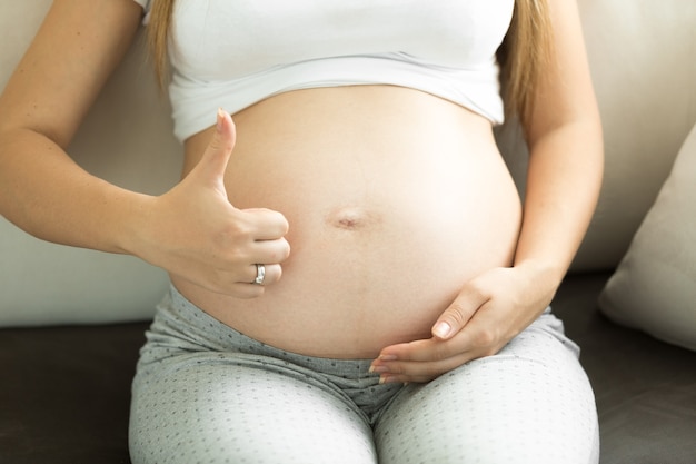 Imagem aproximada de mulher grávida mostrando o polegar para cima