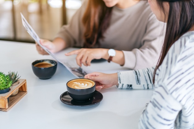 Imagem aproximada de pessoas conversando, lendo jornal e tomando café pela manhã