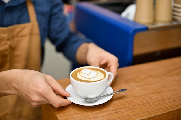 Imagem aproximada de um barista servindo um belo latte no conceito de comida e bebida de mesa de madeira