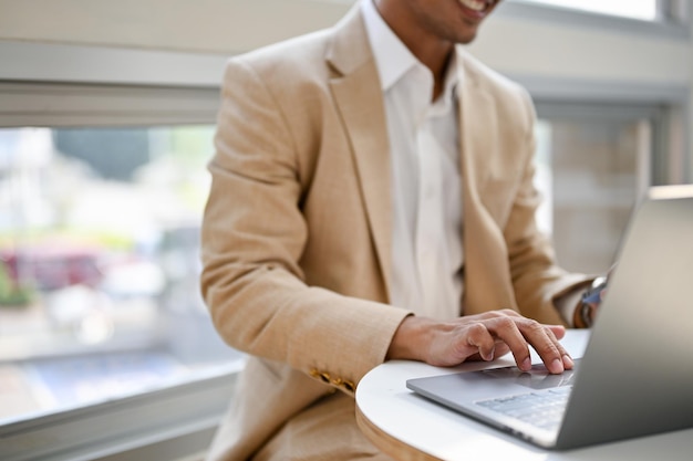 Imagem aproximada de um empresário asiático trabalhando remotamente em um café usando seu laptop