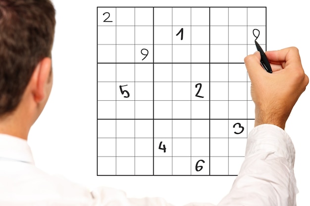 Imagem aproximada de um homem resolvendo sudoku sobre fundo branco