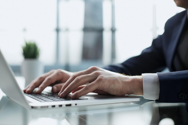 Imagem aproximada de um homem trabalhando e digitando no teclado do computador portátil