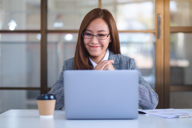 Imagem aproximada de uma bela empresária usando laptop para trabalhar online e videoconferência