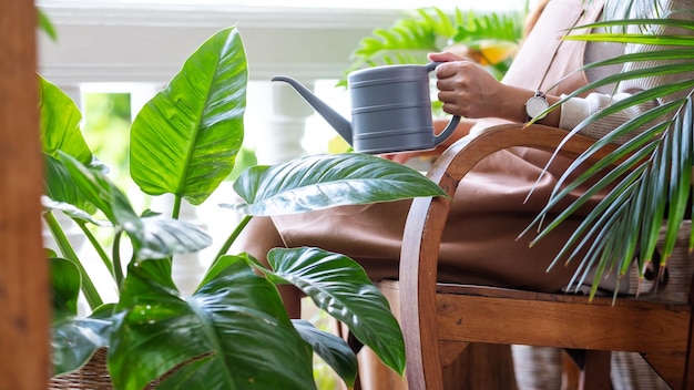 Imagem aproximada de uma bela jovem asiática cuidando e regando plantas de casa regando lata em casa