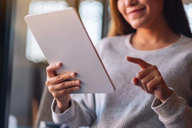 Imagem aproximada de uma bela jovem asiática segurando e usando tablet digital