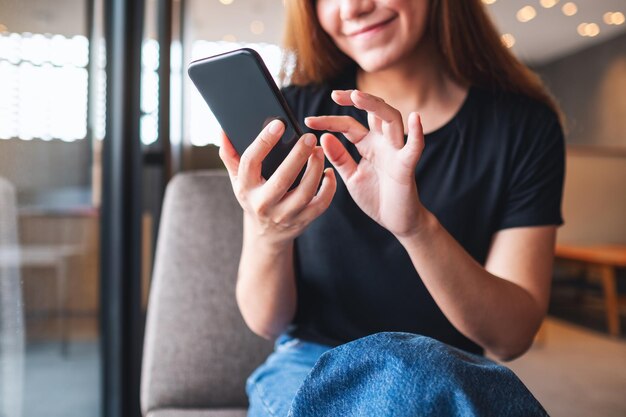 Imagem aproximada de uma bela jovem asiática segurando e usando telefone celular