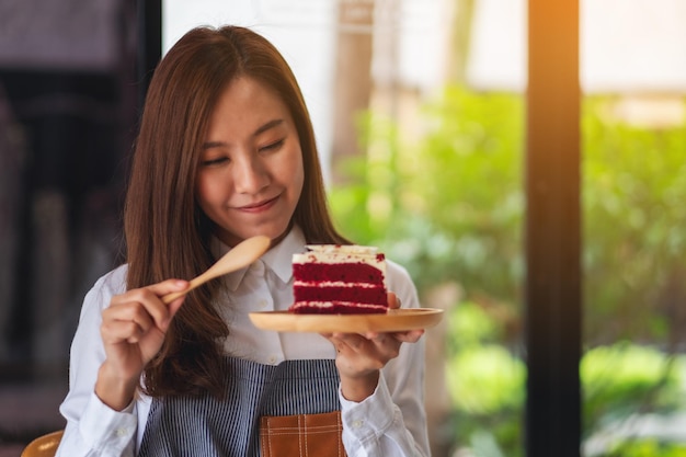 Imagem aproximada de uma chef feminina assando e comendo um pedaço de bolo de veludo vermelho na bandeja de madeira