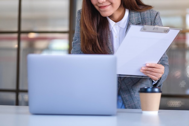 Imagem aproximada de uma empresária asiática usando laptop enquanto trabalhava no escritório