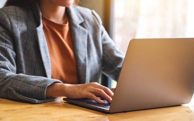 Imagem aproximada de uma empresária trabalhando e digitando no teclado do computador portátil em cima da mesa