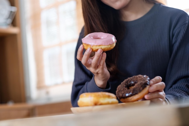 Imagem aproximada de uma jovem segurando e comendo rosquinhas em casa