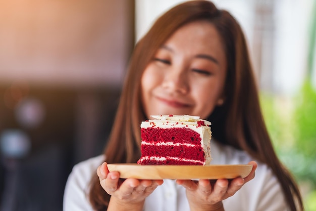 Imagem aproximada de uma linda mulher chef assando e comendo um pedaço de bolo de veludo vermelho em bandeja de madeira