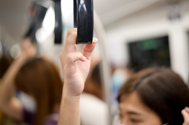 Imagem aproximada de uma mão de mulher segurando o corrimão em transporte público (metrô, trem do céu)