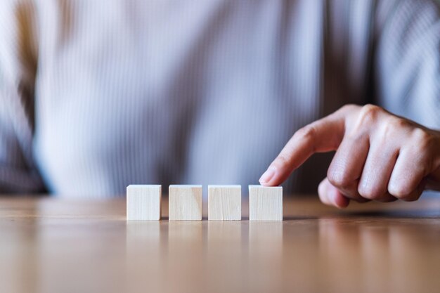 Imagem aproximada de uma mão escolhendo e escolhendo um bloco de cubo de madeira em branco