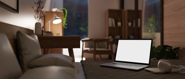 Foto imagem aproximada de uma maquete de laptop com tela branca na cama em um quarto moderno e confortável