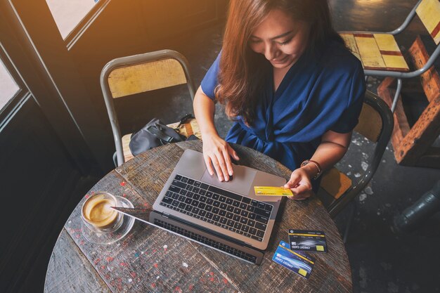 Imagem aproximada de uma mulher de negócios segurando um cartão de crédito enquanto usa um laptop