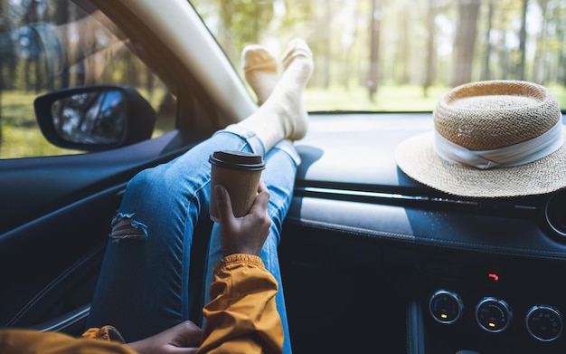 Imagem aproximada de uma mulher deitada e tomando café no carro