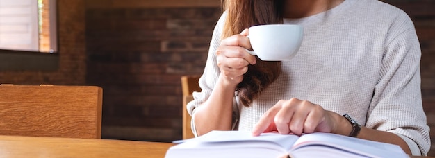 Imagem aproximada de uma mulher lendo um livro enquanto toma café