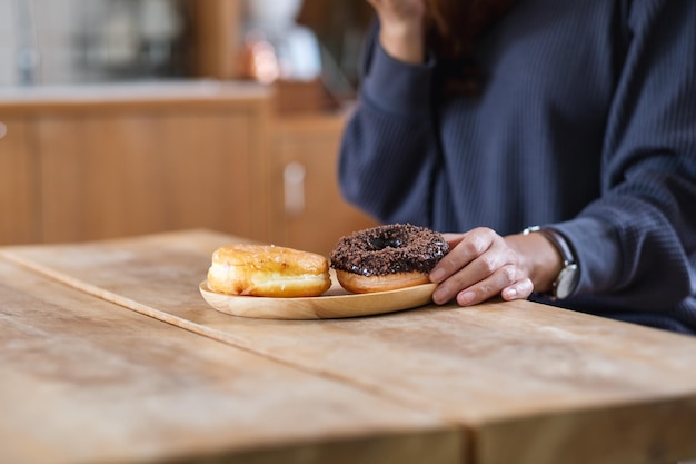 Imagem aproximada de uma mulher segurando e comendo rosquinha em casa