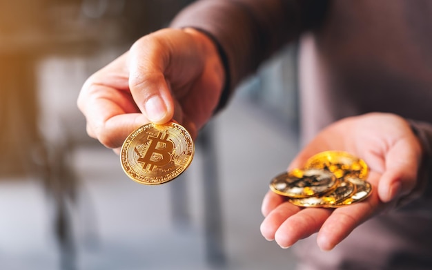 Imagem aproximada de uma mulher segurando e dando bitcoins de cor dourada