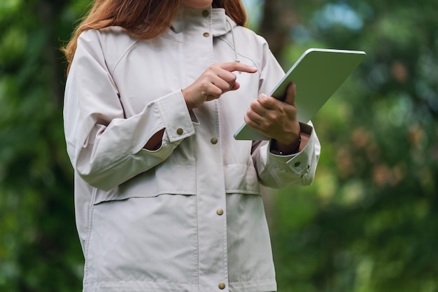 Imagem aproximada de uma mulher segurando e usando tablet digital ao ar livre