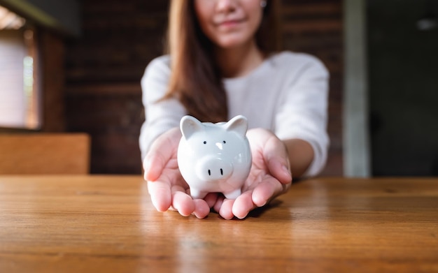 Imagem aproximada de uma mulher segurando um cofrinho para economizar dinheiro e conceito financeiro
