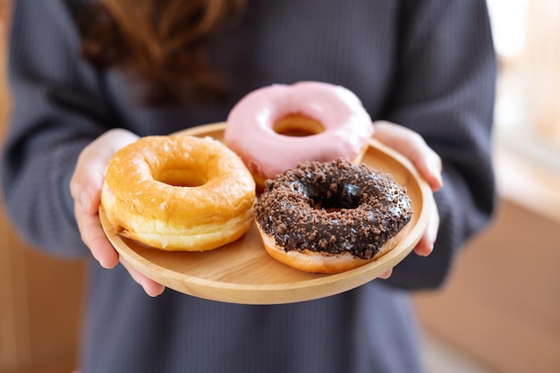 Imagem aproximada de uma mulher segurando um prato de donuts na cozinha em casa