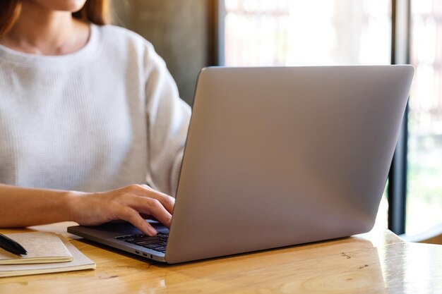 Imagem aproximada de uma mulher trabalhando e digitando no teclado do computador portátil em cima da mesa
