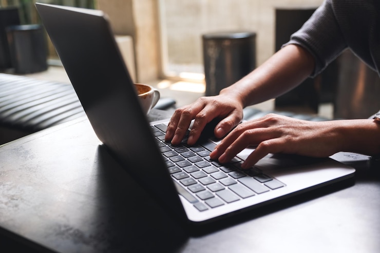 Foto imagem aproximada de uma mulher trabalhando e digitando no teclado do computador portátil na mesa de madeira